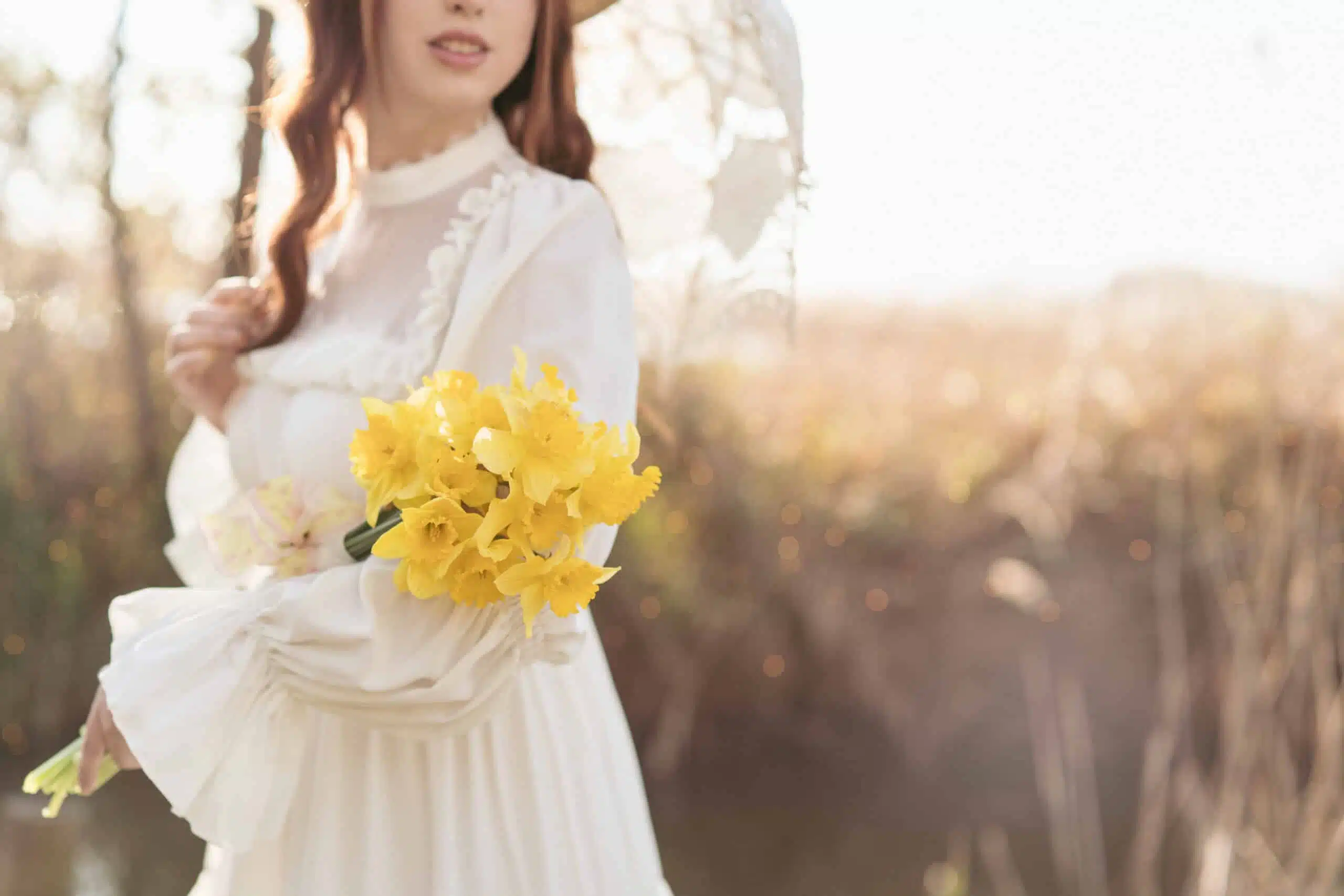 young woman holding yellow flowers outdoor.