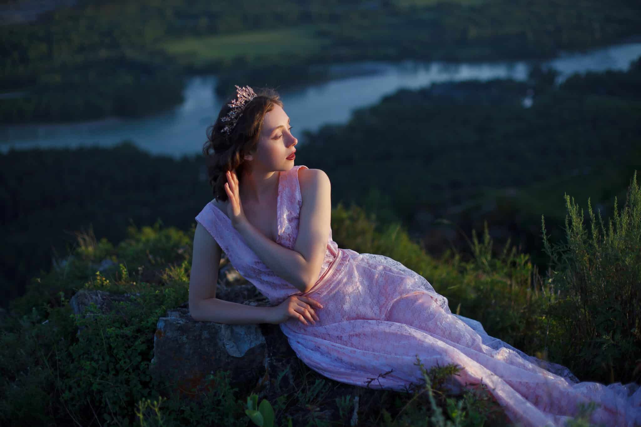 on top of a mountain, a princess in a pink dress with a long train