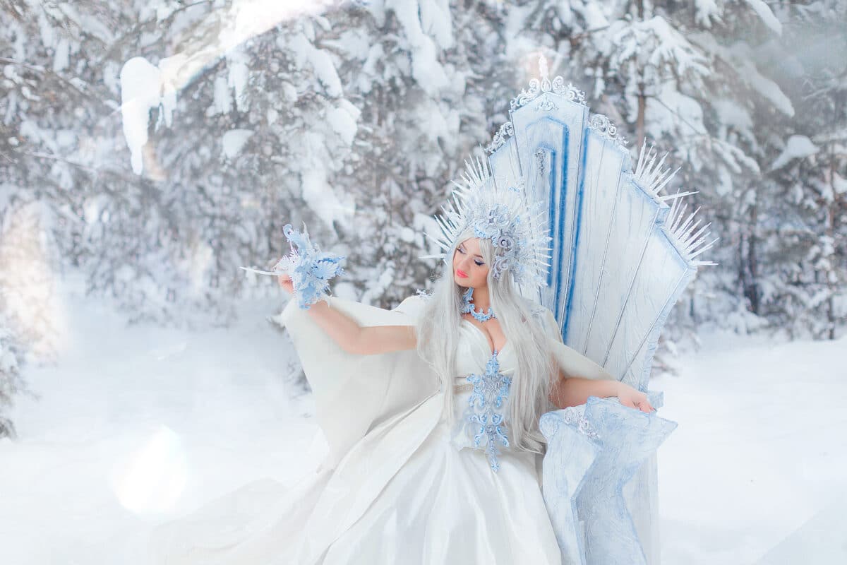 Young girl snow queen in the forest. The crown of the snow queen, the throne of ice. The queen's puffy dress. Diadem. Fabulous snowy forest. Fantasy concept