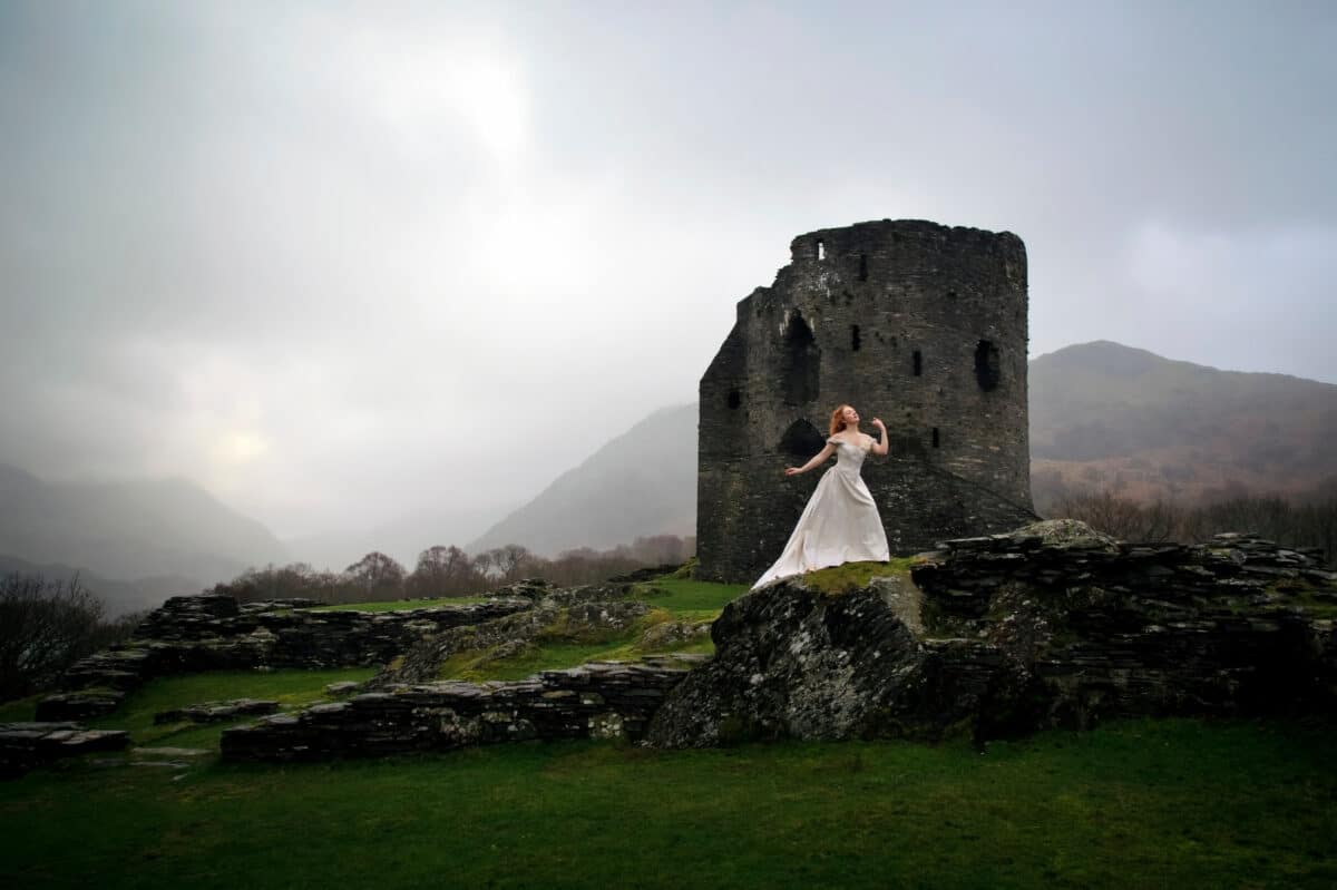 Woman in long white dress posing in front of a Castle Keep