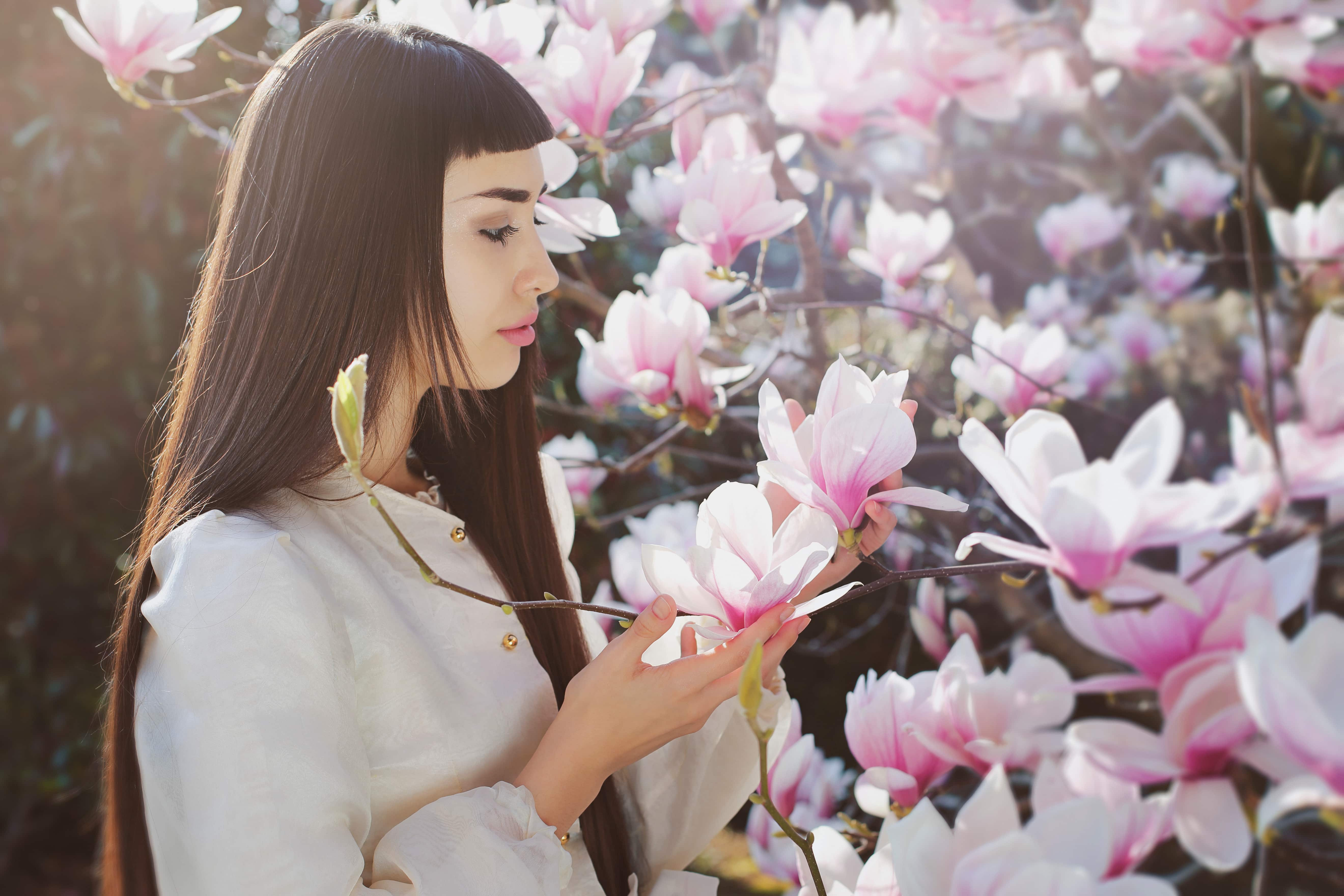 Beautiful young woman among spring flowers and light