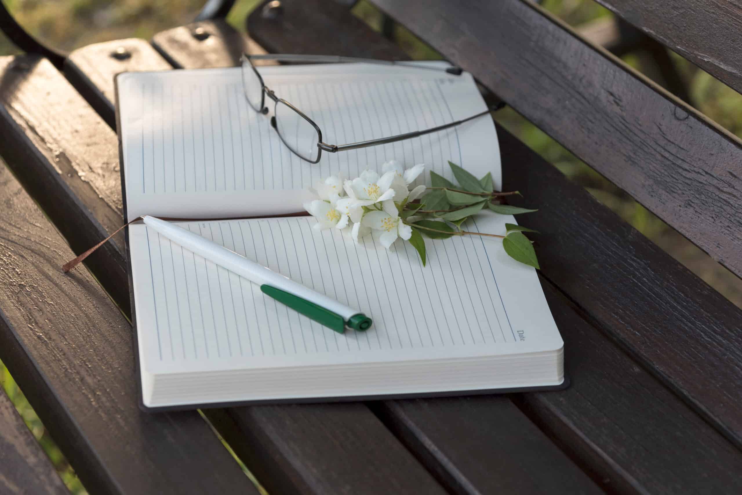 Diary, reading glasses, Jasmine flowers on the park bench.