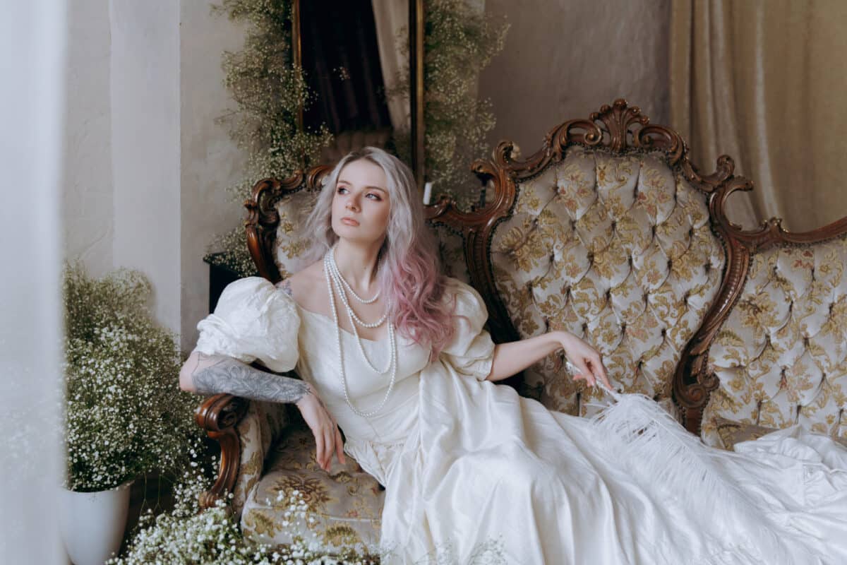 A luxurious girl with a beautiful make-up and hairstyle in a vintage vintage dress woke up in the morning in bed and sits on the sofa at the piano and poses as a model