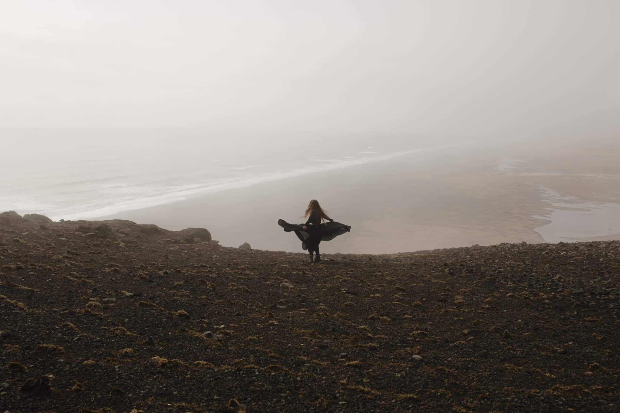 Woman in black dress in the fog on a cliff
