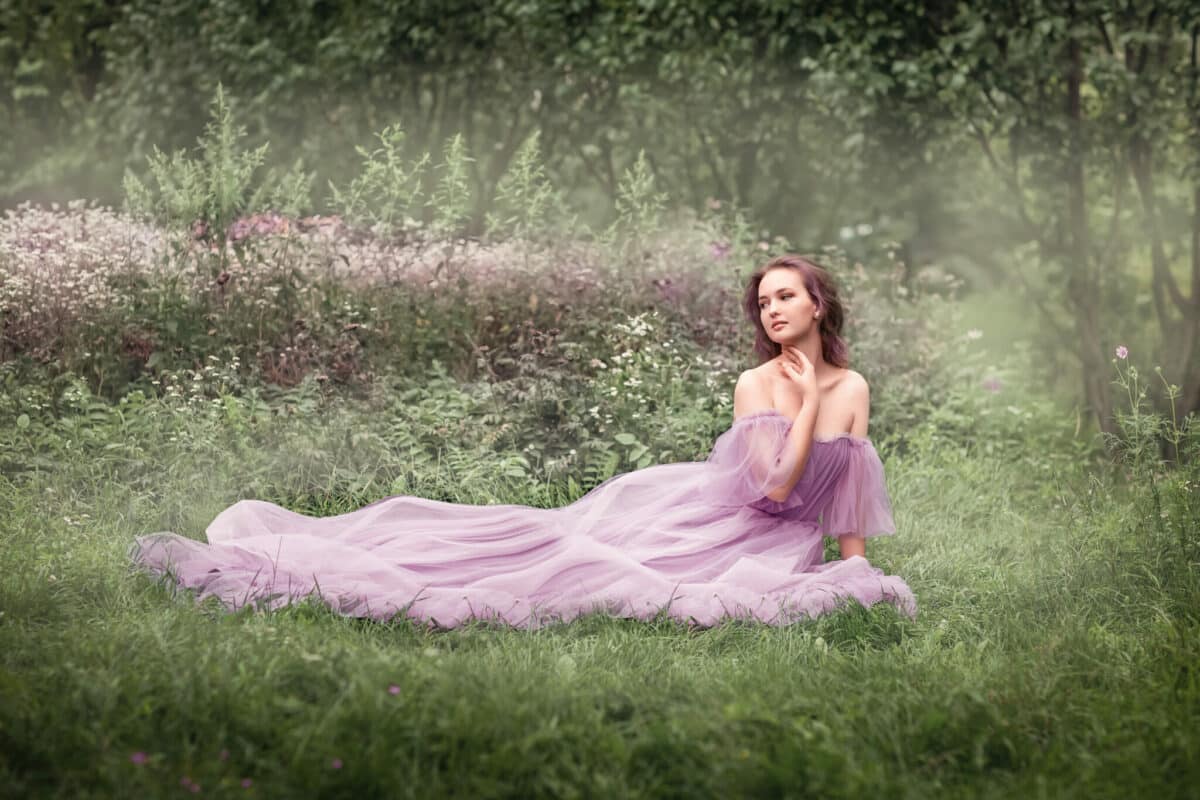 the lady in lavender dress is sitting in the grass