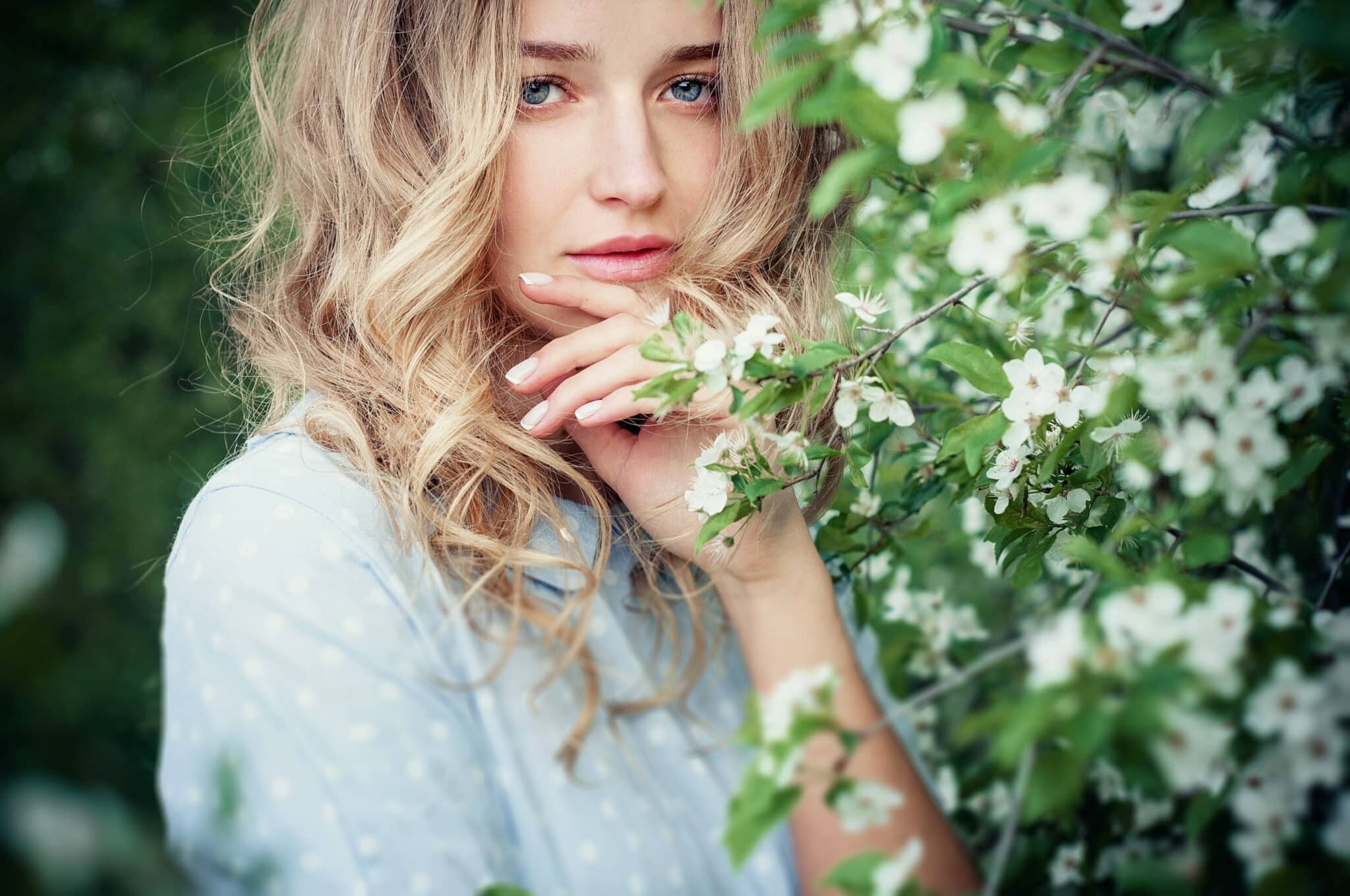 Beautiful happy young woman enjoying the spring flowers