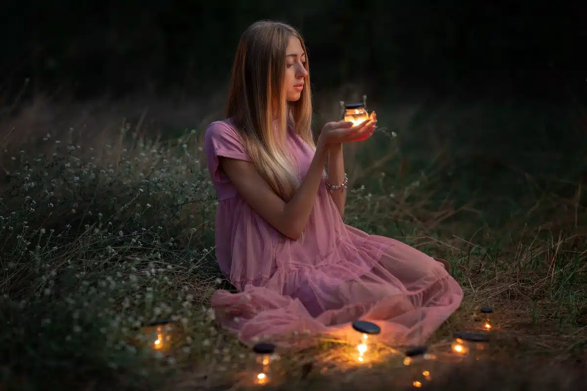 beautiful girl holding a jar of fire in a fairy forest