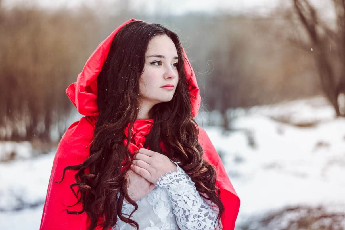fairy lady with a red hood standing in the winter forest