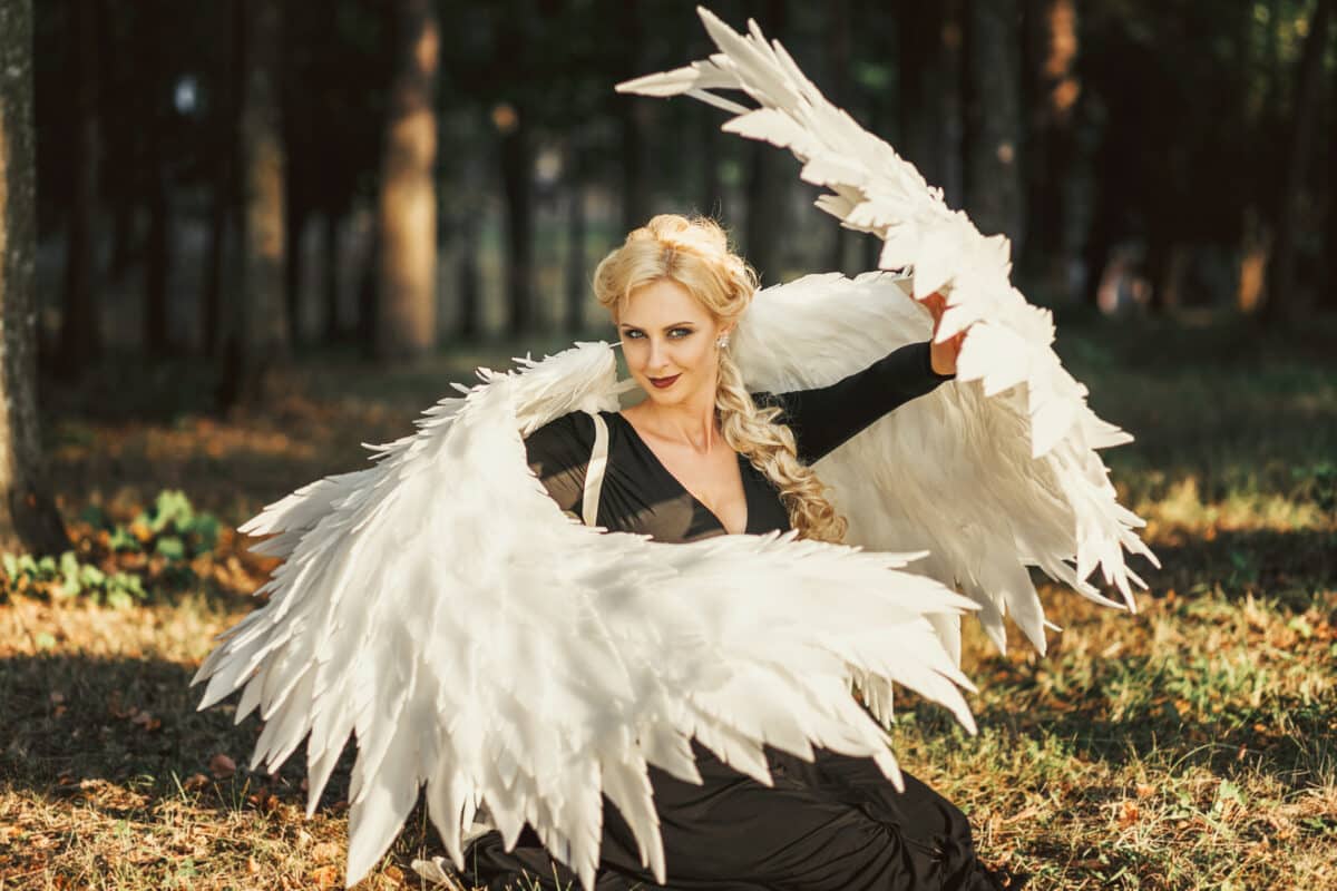 Fallen black angel with wings in magic forest outdoots. Sexual woman