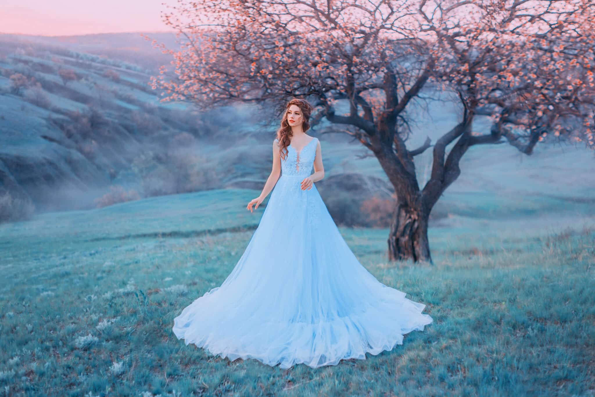 incredible woman stands in the background of a mountain landscape in a blue dress.