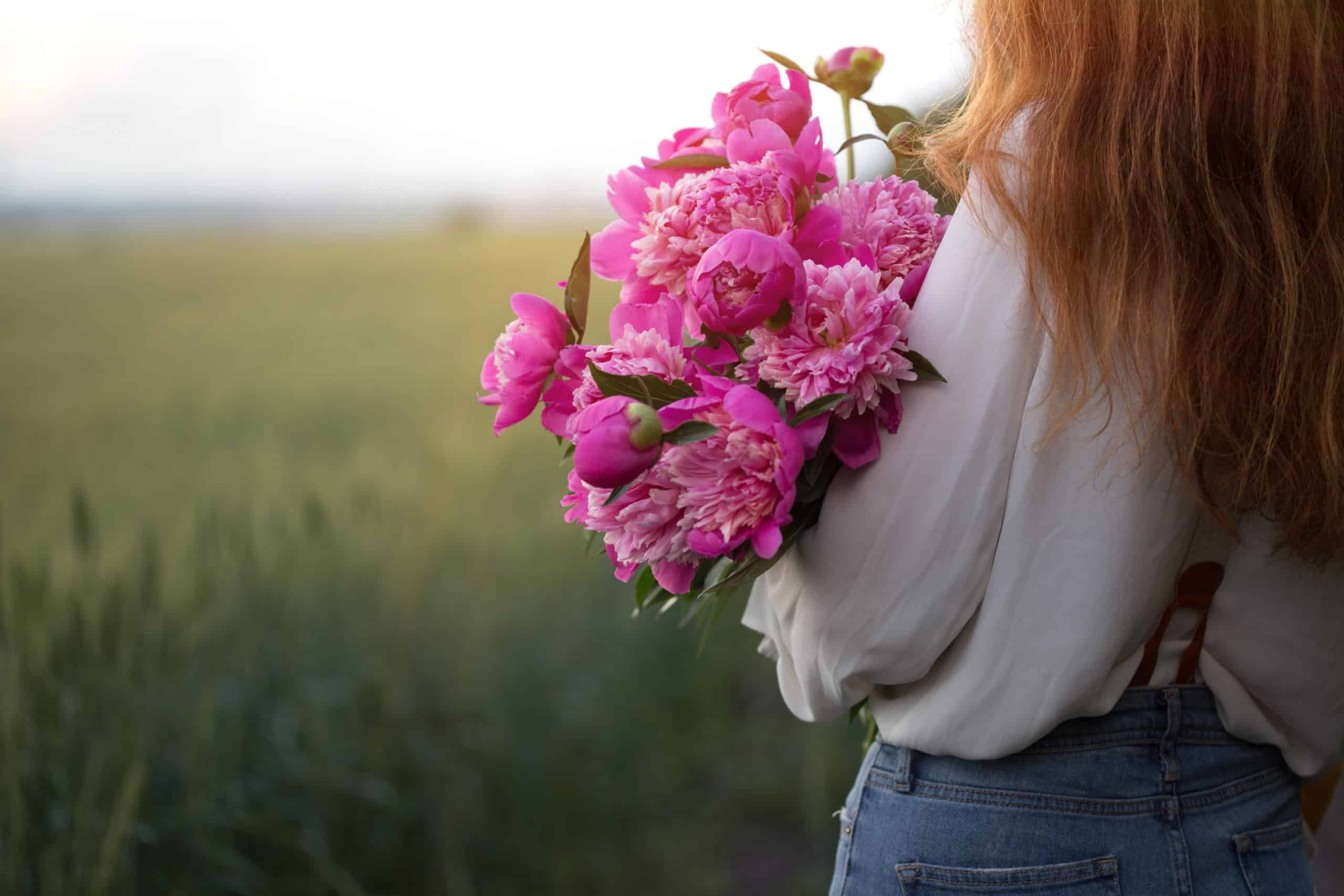Outdoors, a beautiful girl with a bouquet peony