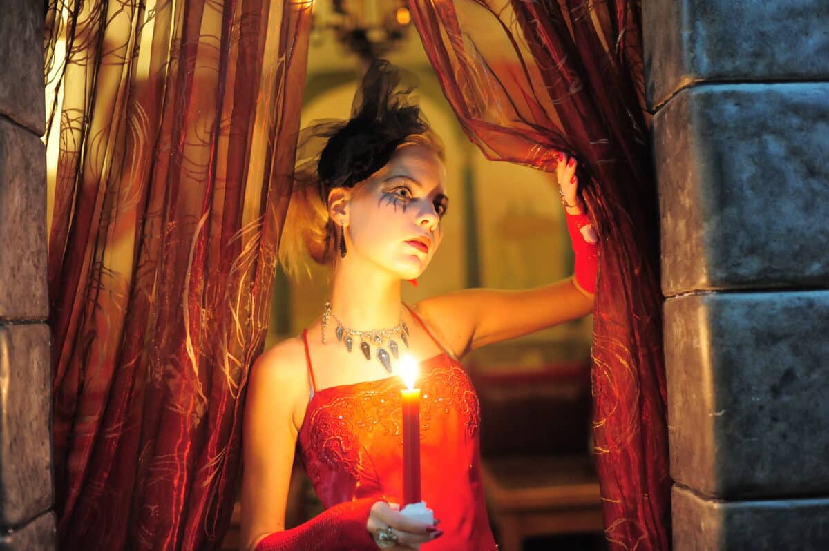 noble lady in red with a candle in the dark