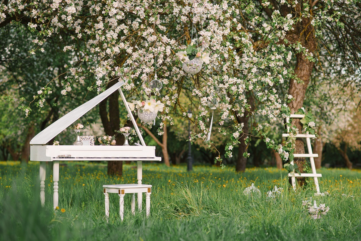 White grand piano and white staircase outdoors in spring.