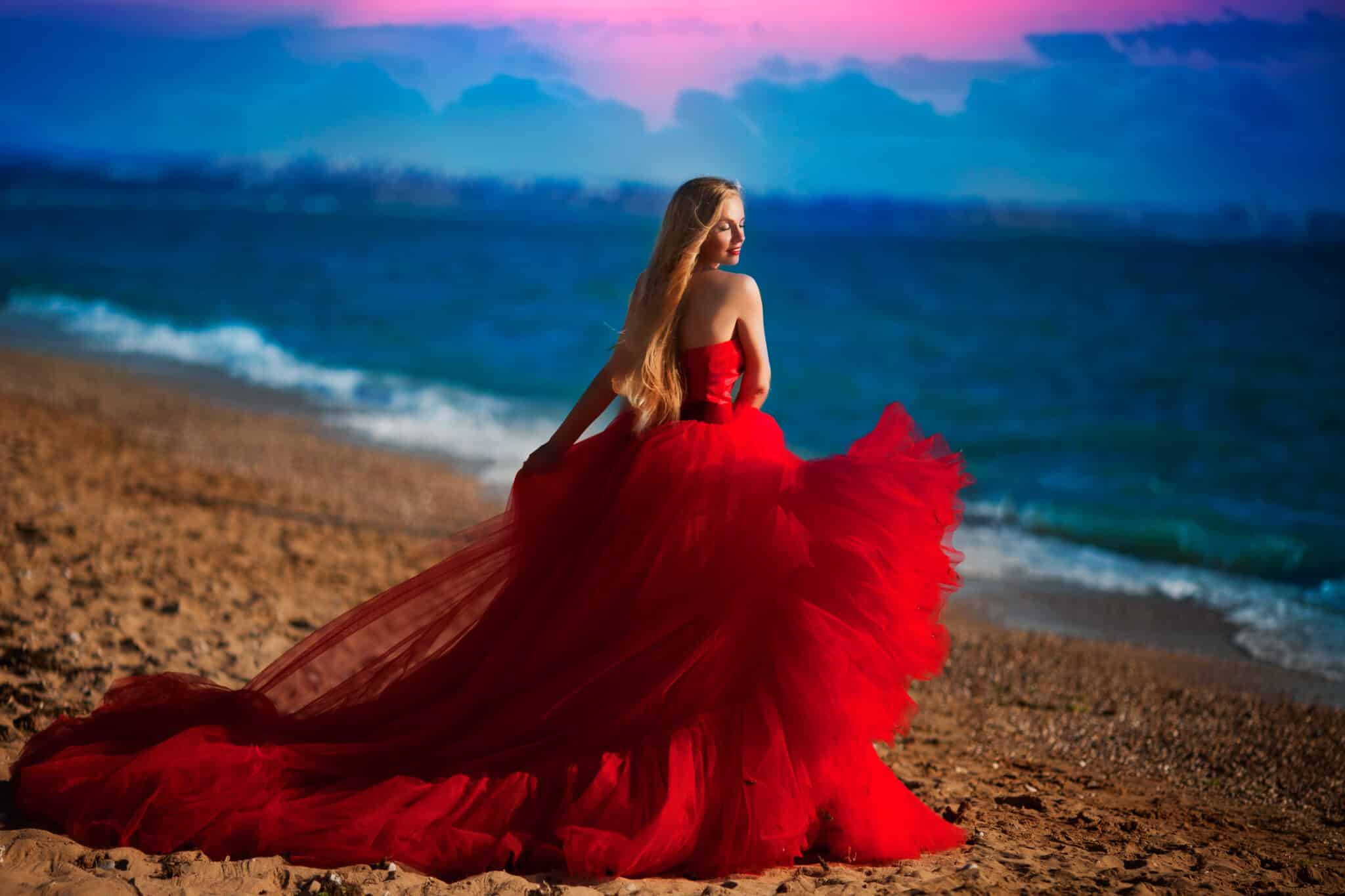 a woman in a red dress on the beach