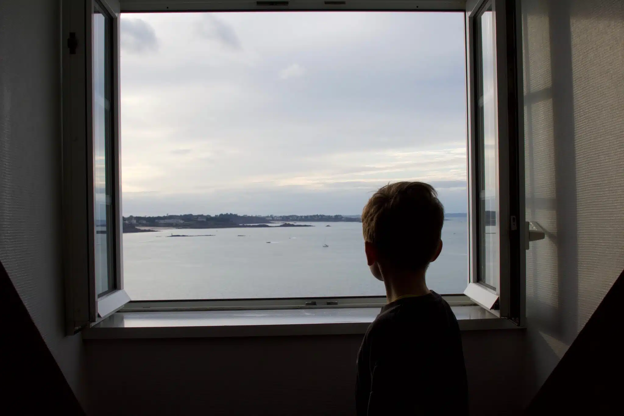A child looking the sea by the window