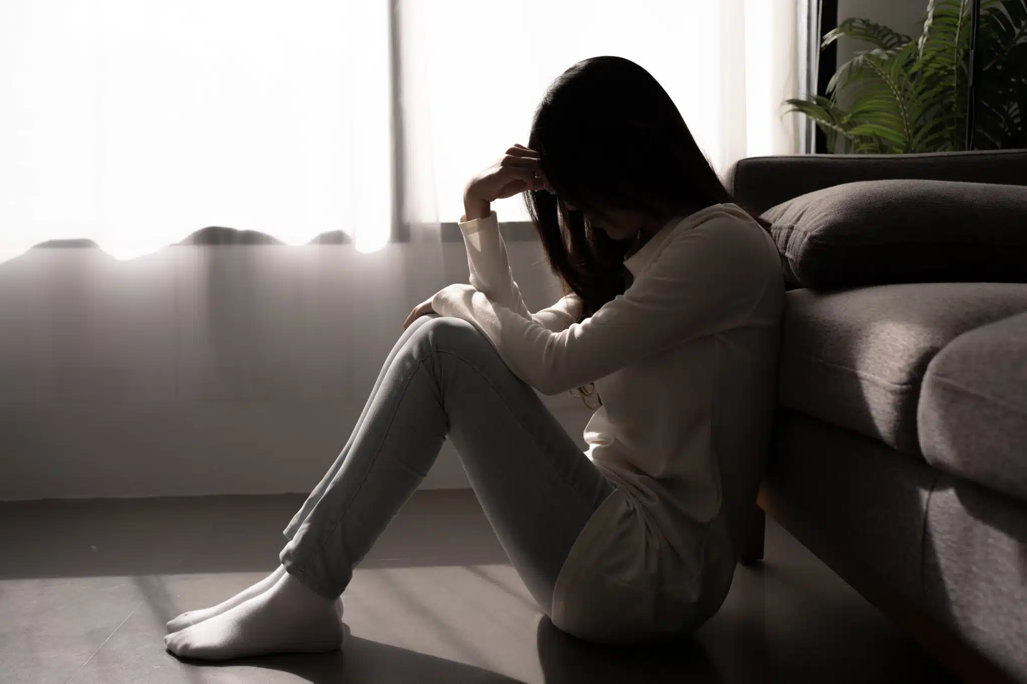 Young woman feeling depressed and stressed sitting in dark bedroom