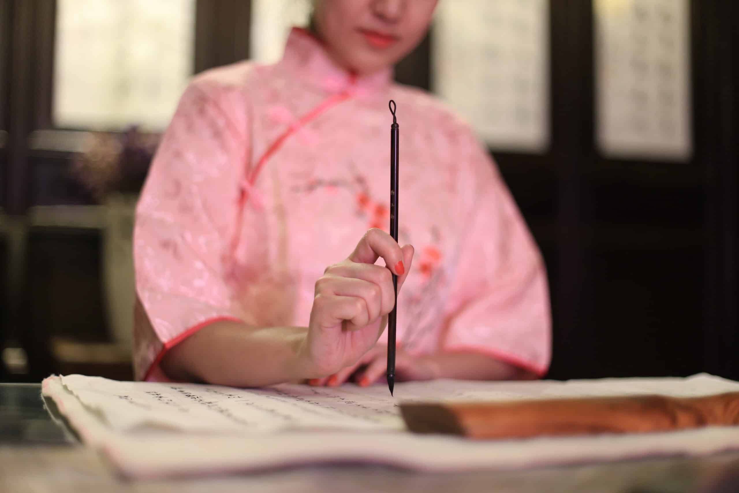 a woman in pink Chinese traditional costume with Chinese writing.
