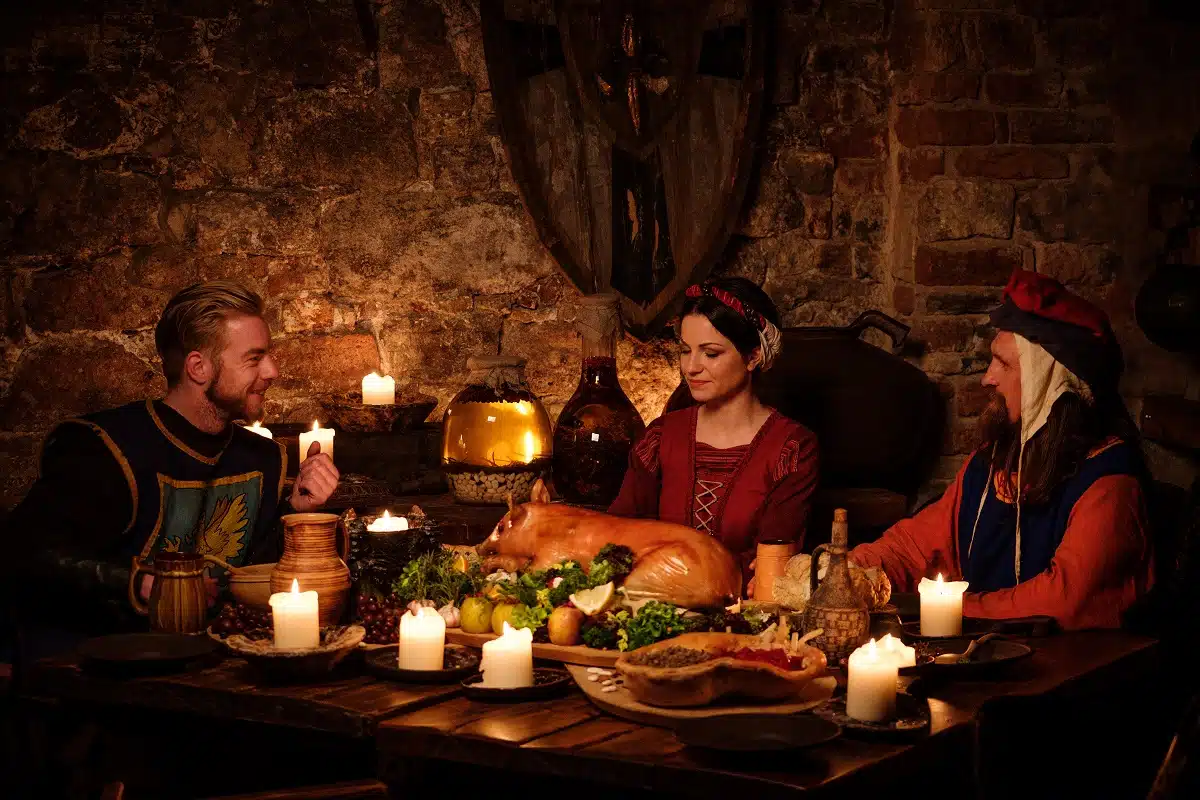Medieval people eat and drink in ancient kitchen in the castle