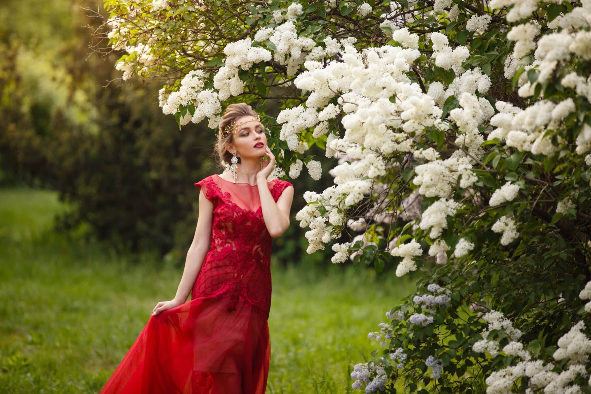 Beautiful woman in red dress in blooming spring garden