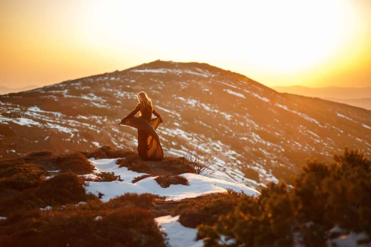 lady in a red dress on top of the mountain at sunrise