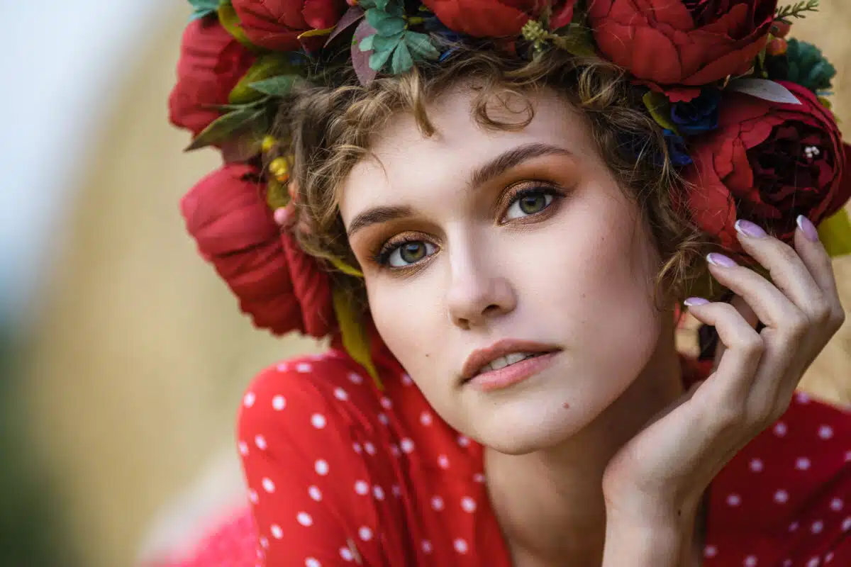 A young pretty woman in a red dress with a head wreath made of red flowers