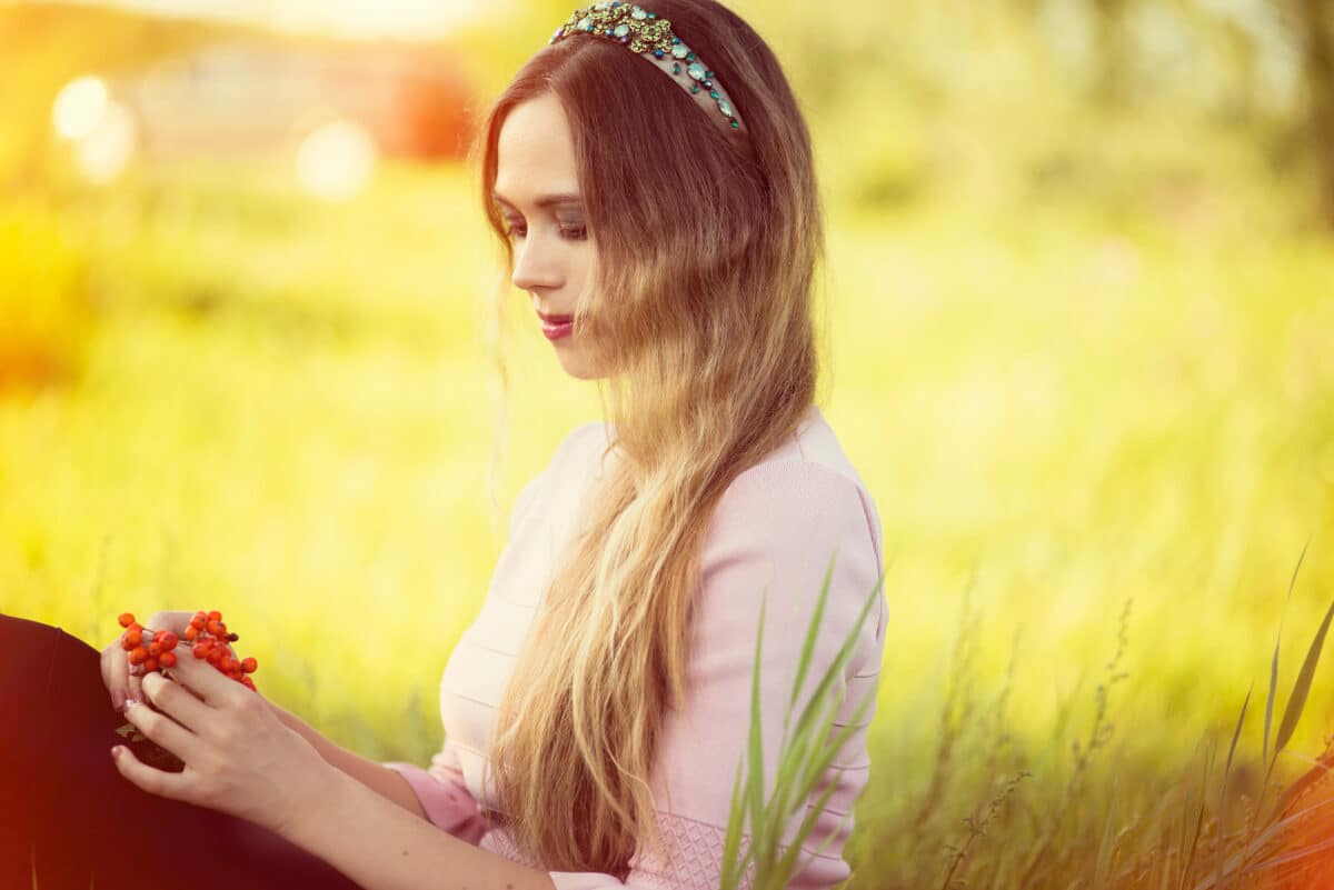 A lady standing in the field with birch berries in her hands