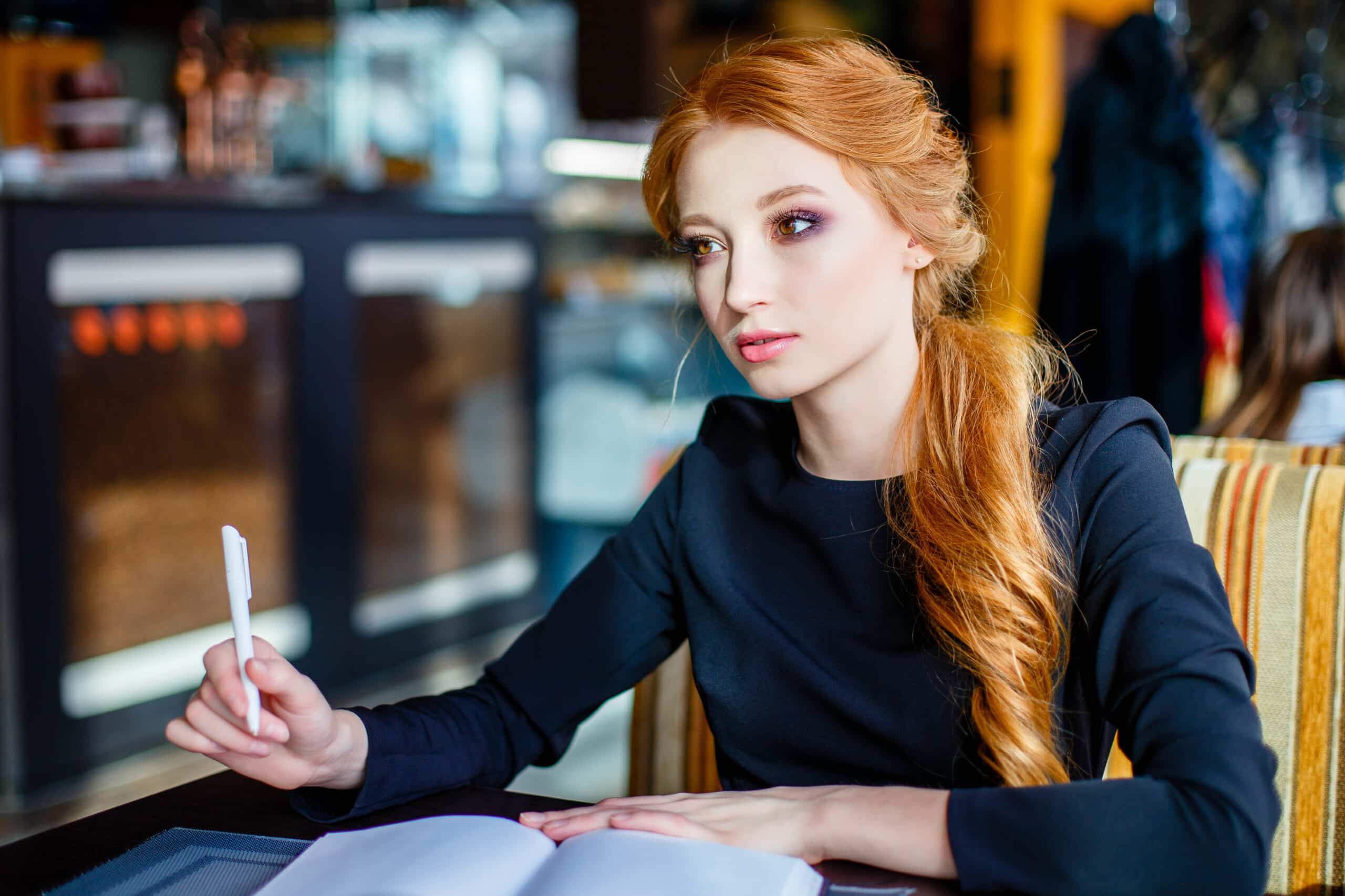 Young woman redhead writing in a cafe