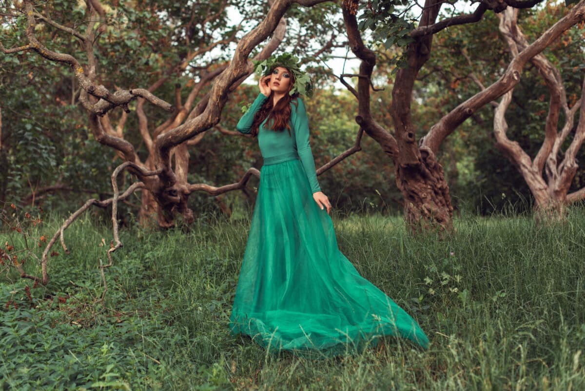 wood nymph dressed in green standing near the trees