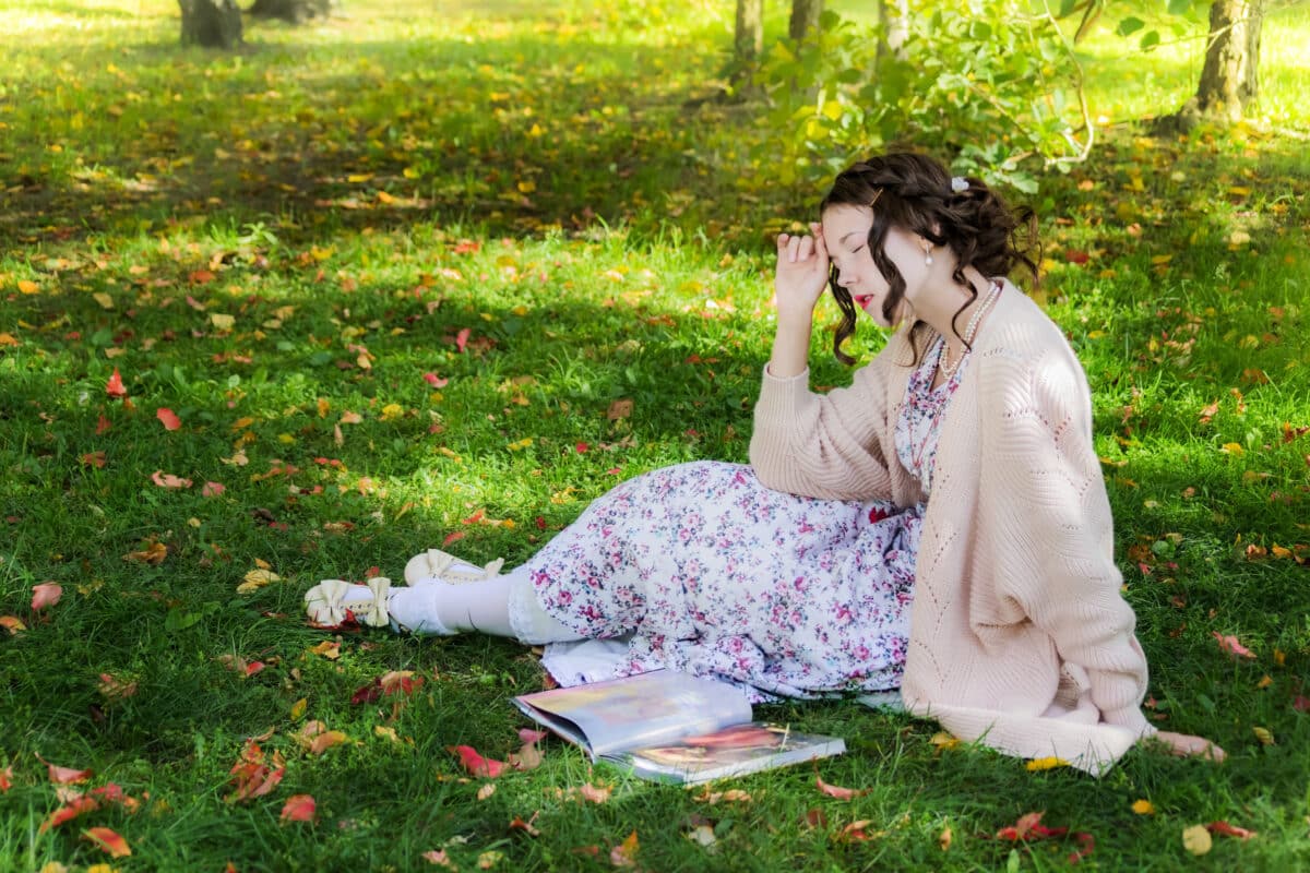 Tired woman is sitting under a tree and reading book