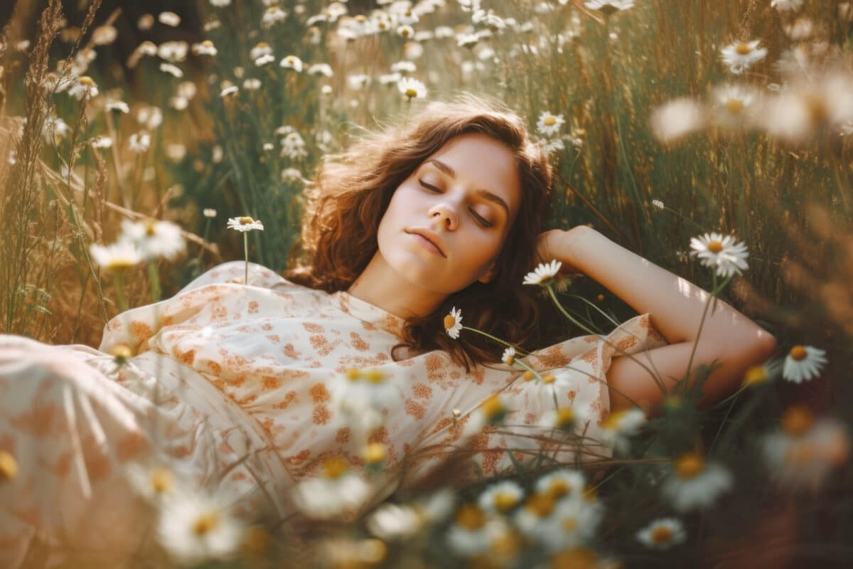 Beautiful young woman lying in the field with chamomile flowers