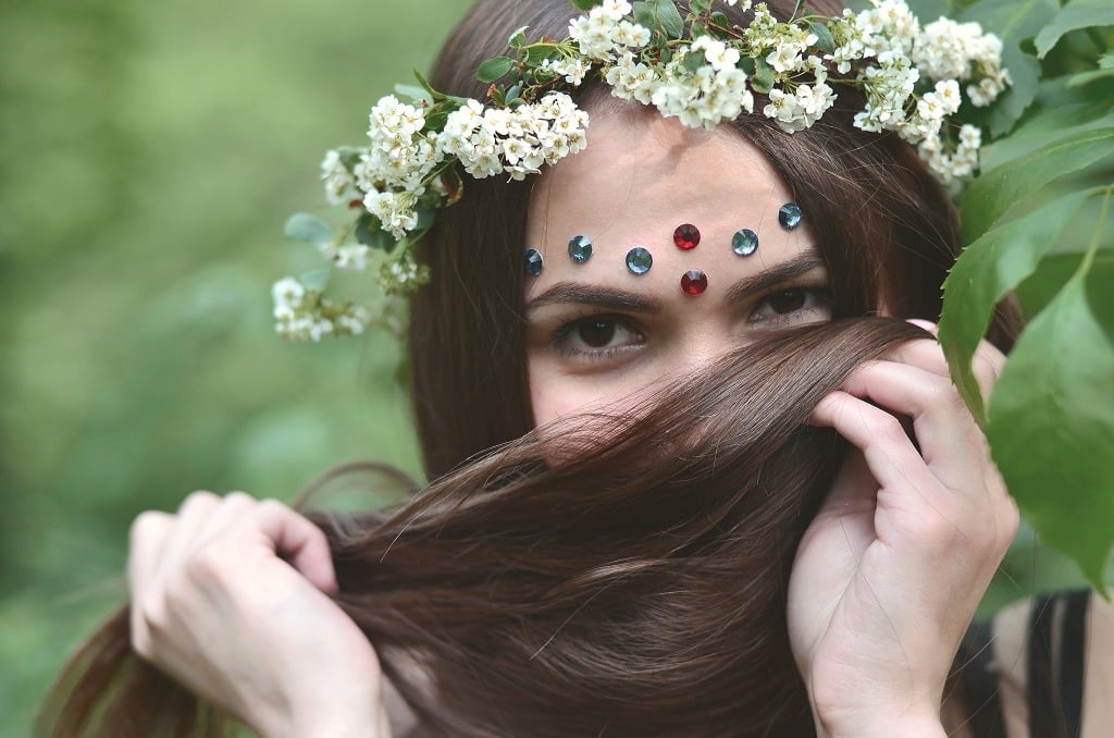 Emotional young girl with a floral wreath on her head and shiny ornaments on her forehead.