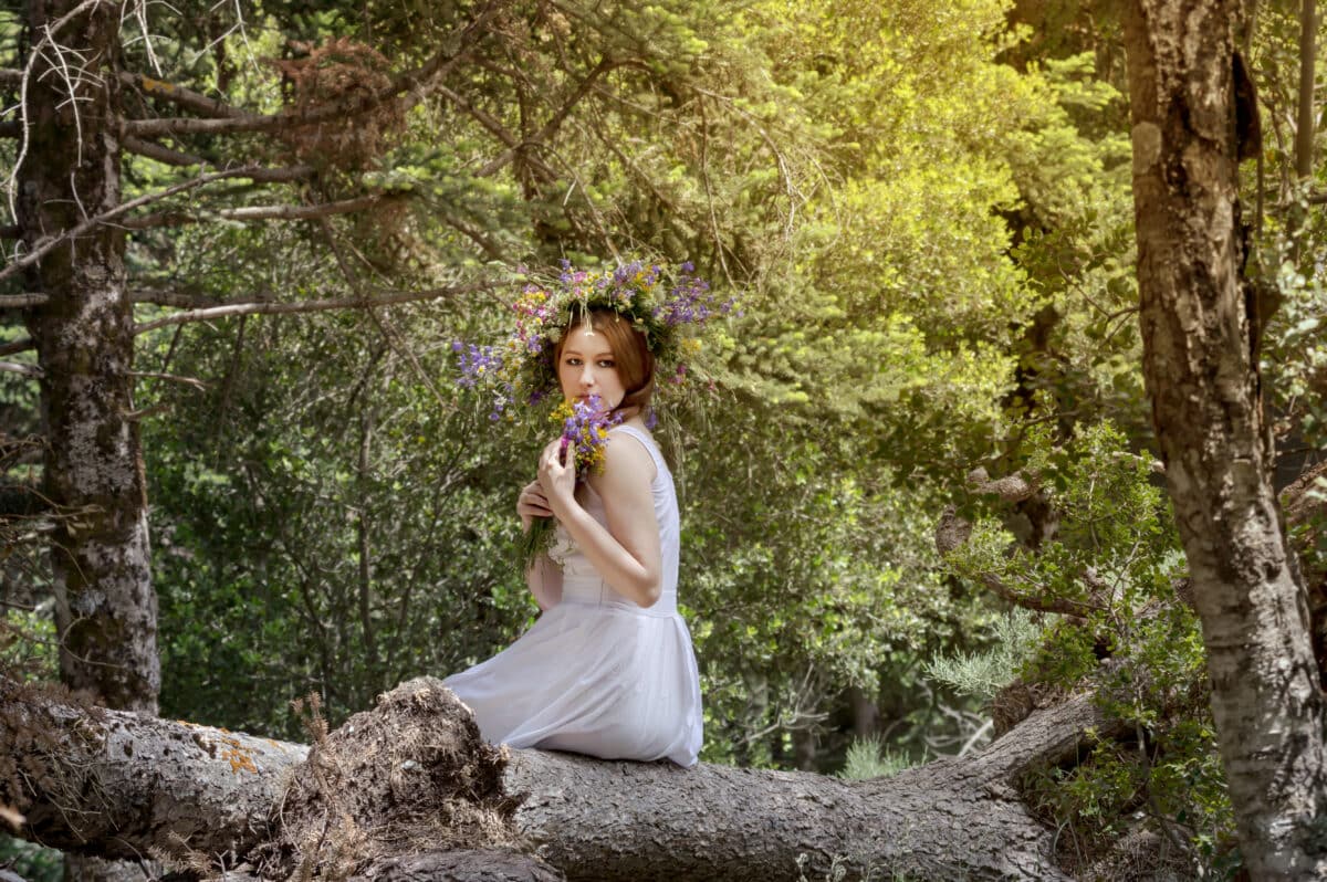 Young girl in the woods with a wreath of wildflowers