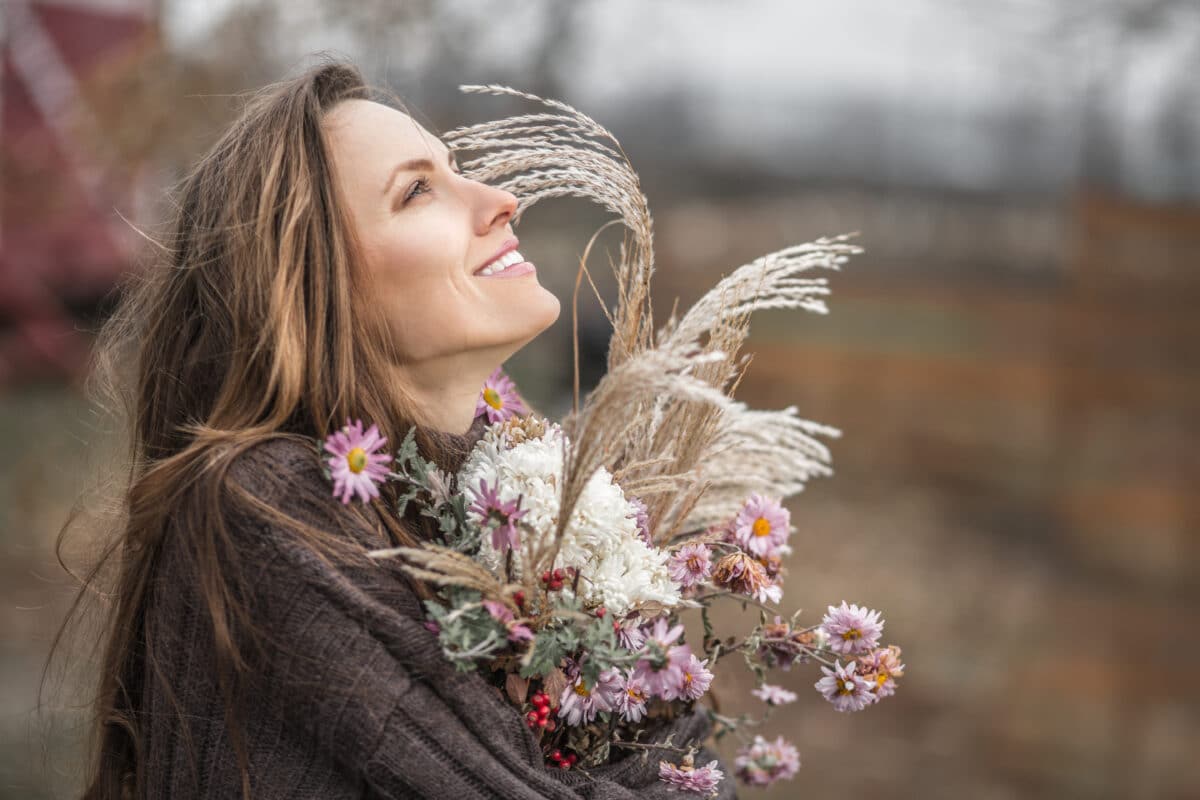 
A beautiful farmer holding autumn flowers in the orchard