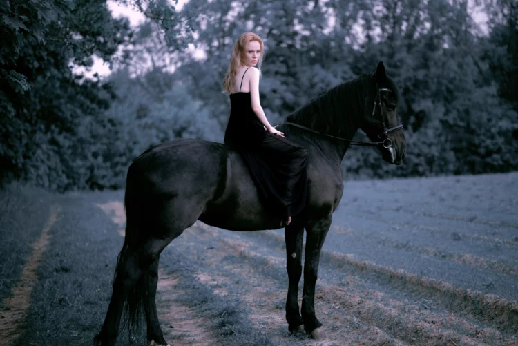 Beautiful young blond woman wearing black dress, riding a black horse, dark gloomy and gothic atmosphere