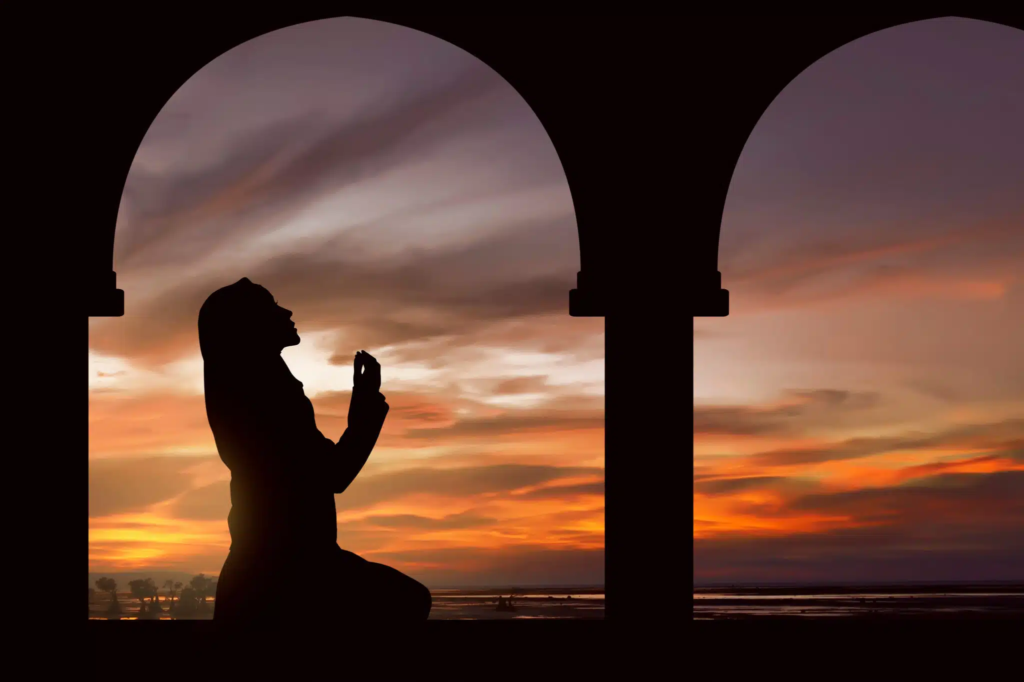 Silhouette of a women praying during sunset