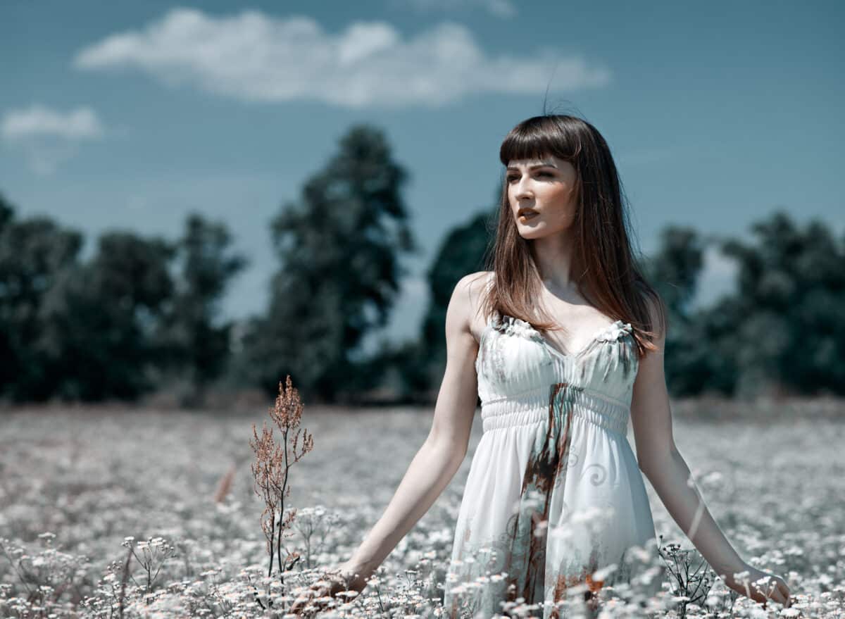 enchanting woman in a white dress standing in the meadow