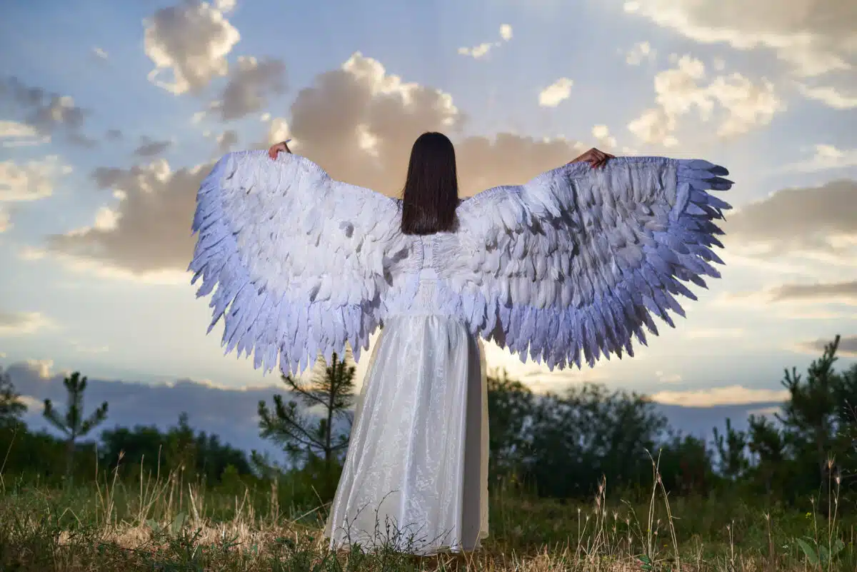 girl stands with her back in white clothes with angel wings
