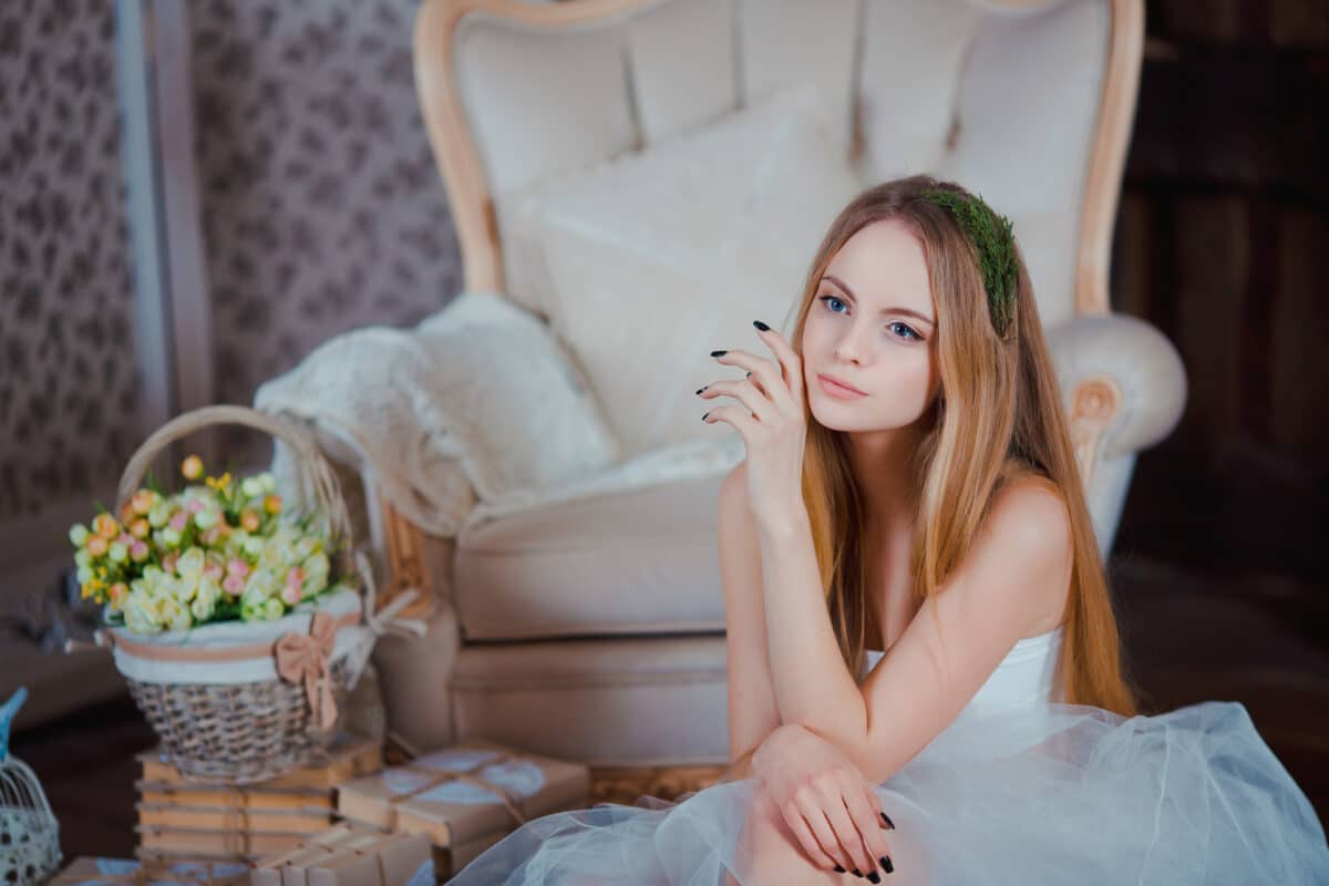 a young beautiful girl with flower wreath sitting indoor