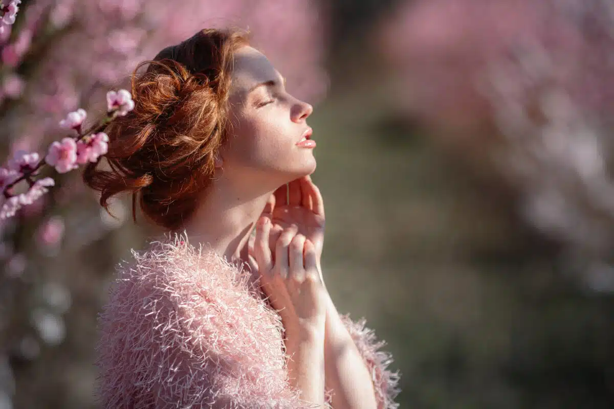 Beautiful young lady with red hair in a blossoming peach garden