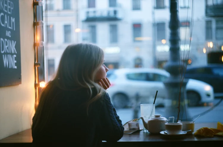 Lonely pensive blonde woman thinking in a coffee shop looking through the window