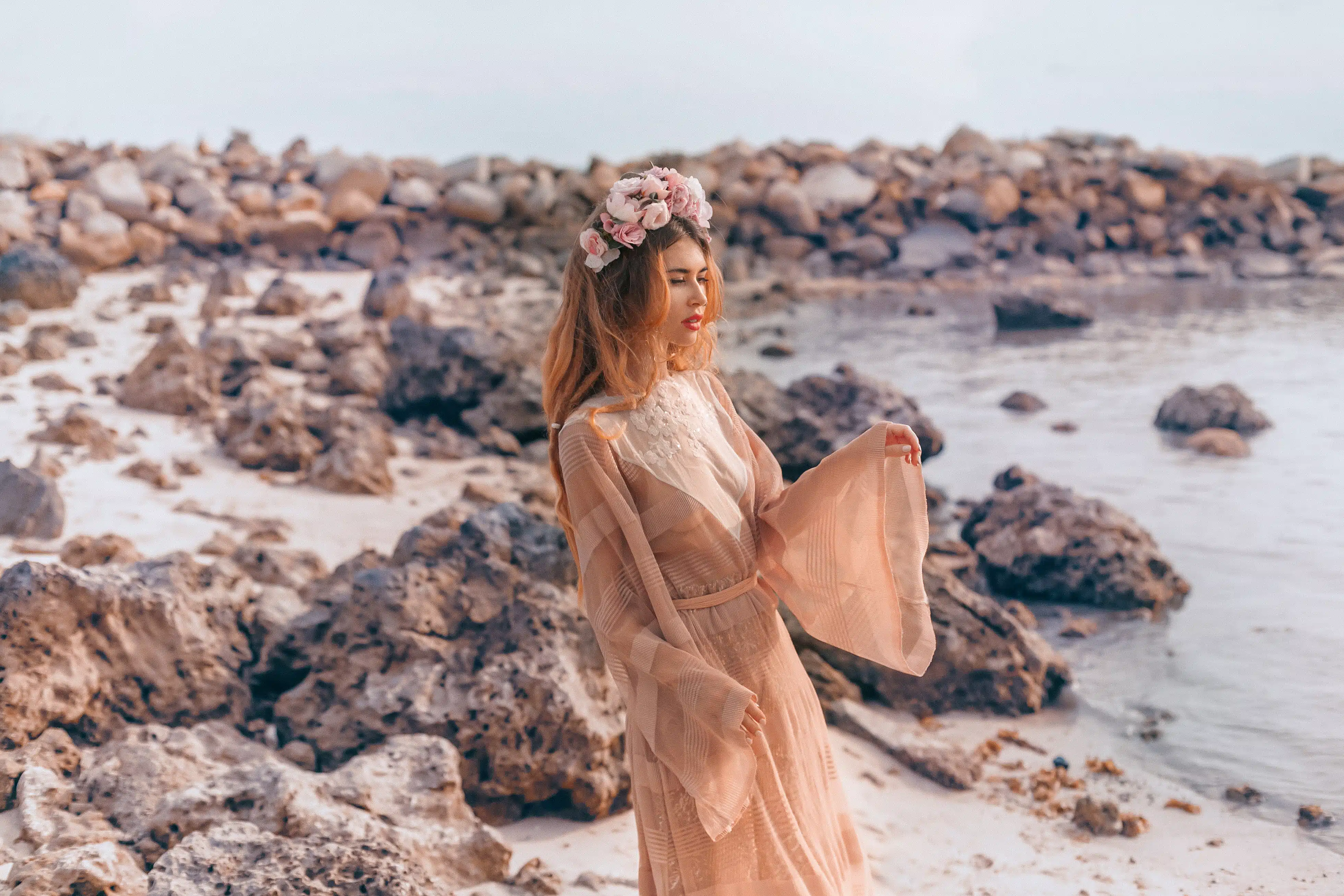 beautiful young woman in boho dress and wreath on the beach at sunrise