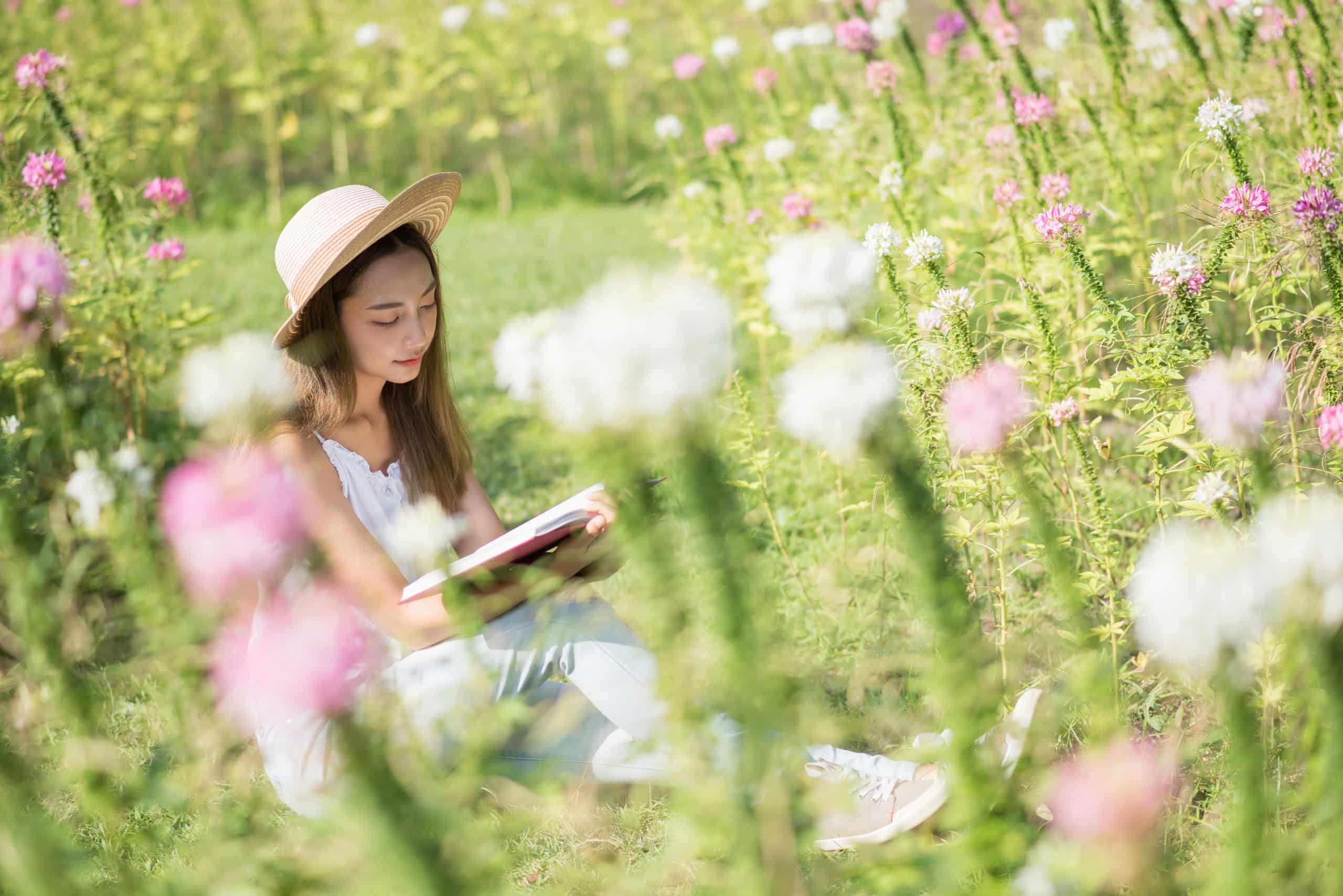 Young woman reads a book at spring flower garden.