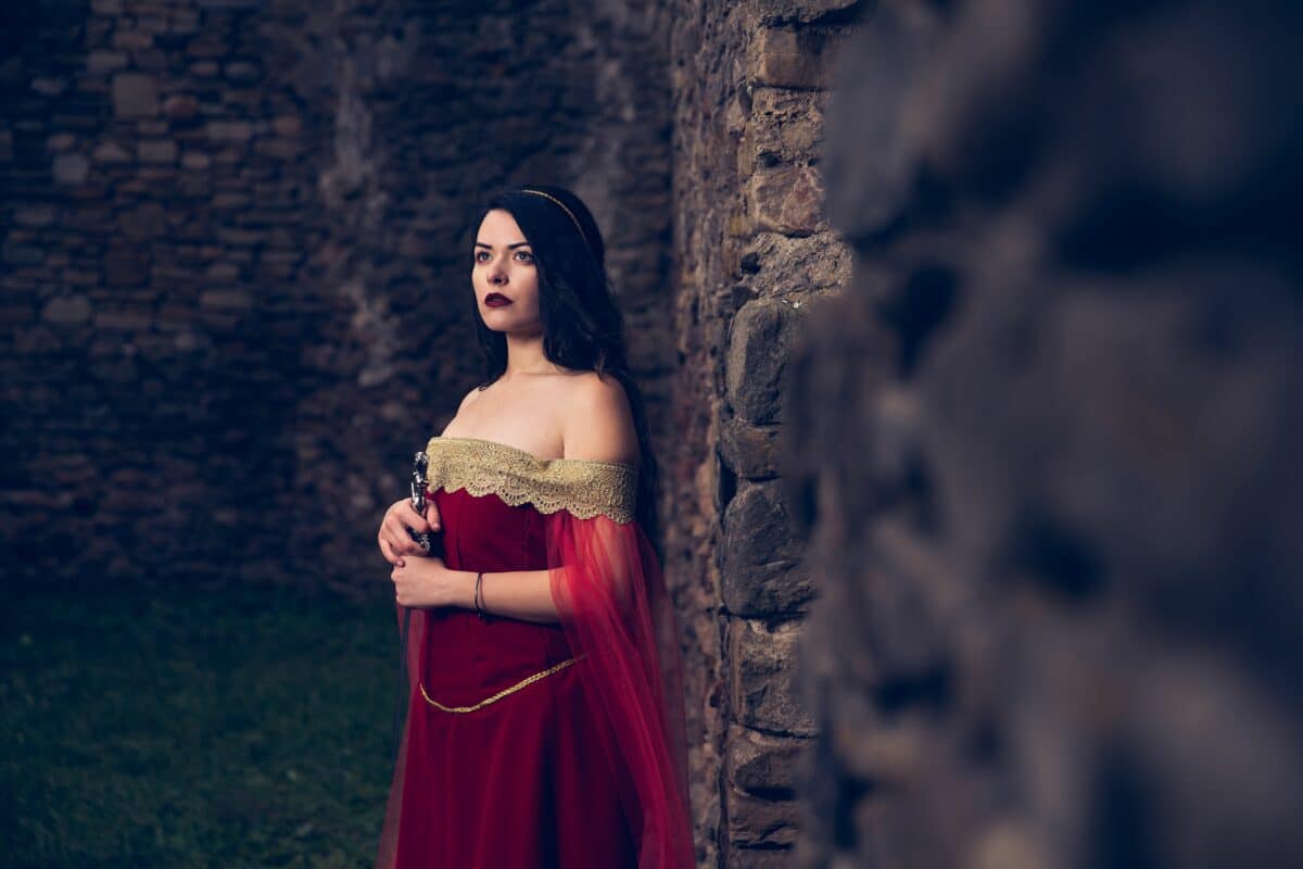 sad noble woman with a sword wearing a medieval red dress