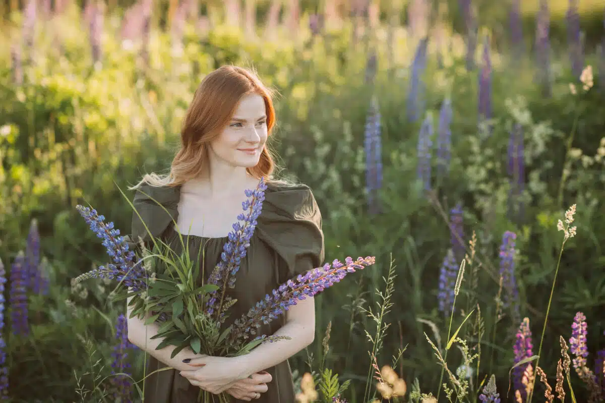 a red-haired lady holding lavender flowers in the field
