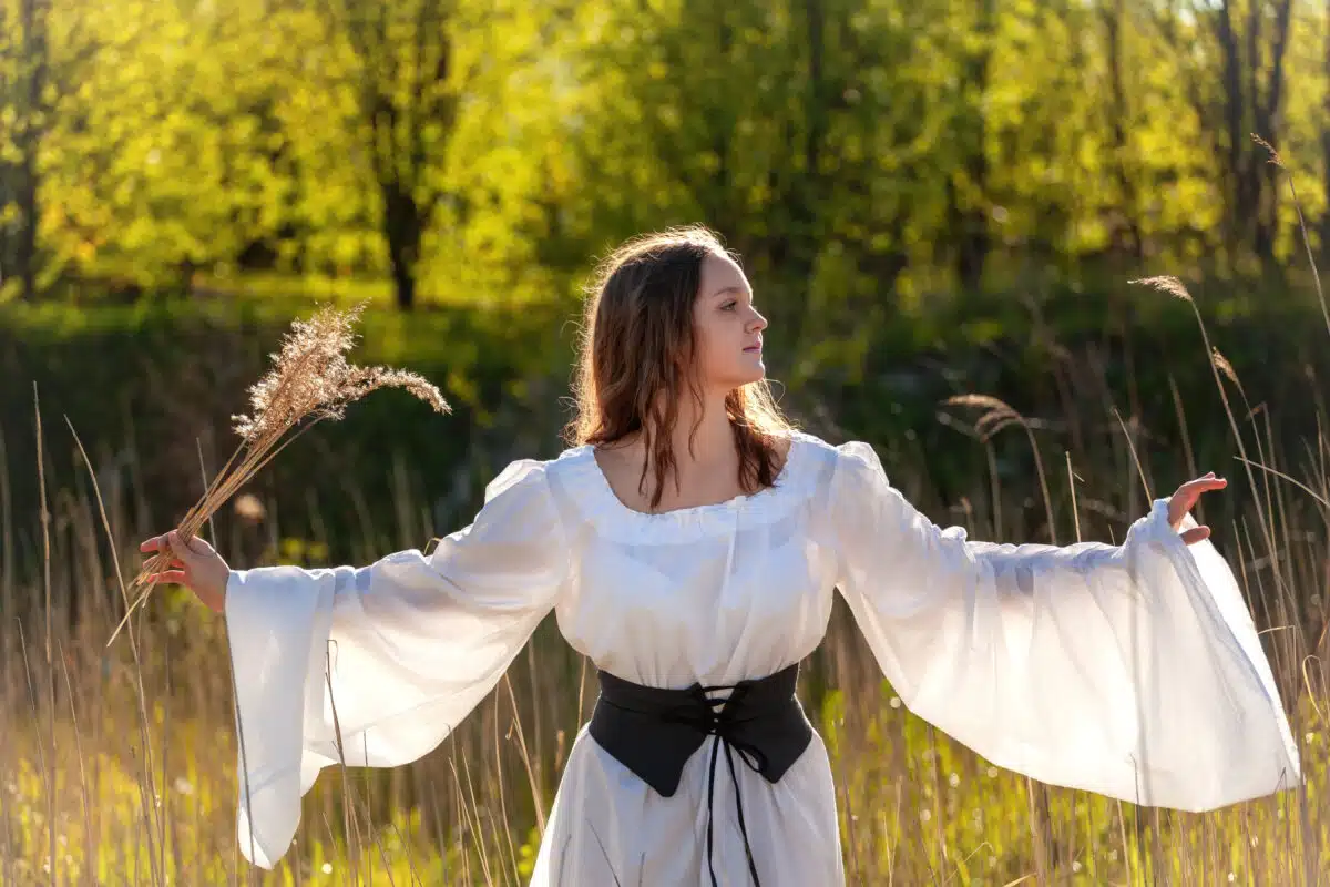 happy medieval young woman in historical female costume in nature
