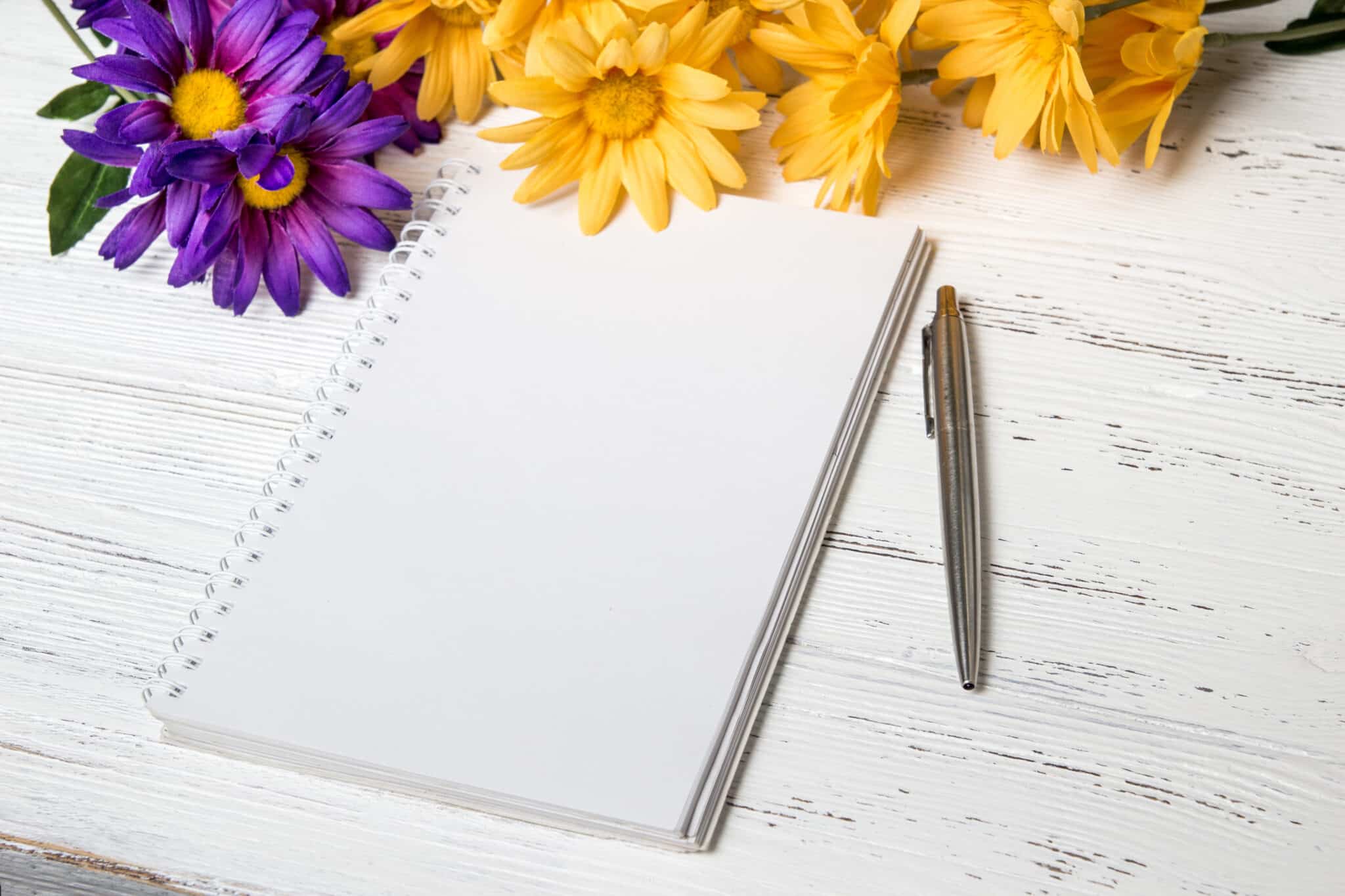 Notebook, pen and flowers on the table