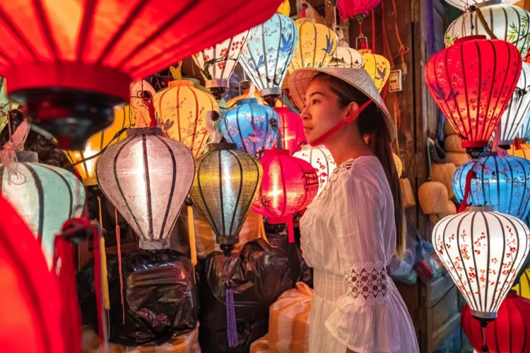 Asian woman looking at pretty bright lanterns in Hoi An, Vietnam