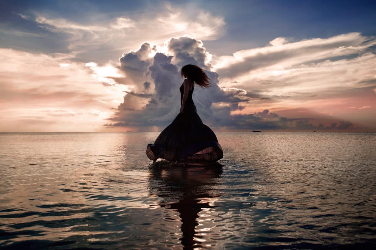 magical woman dancing on the water at sunset