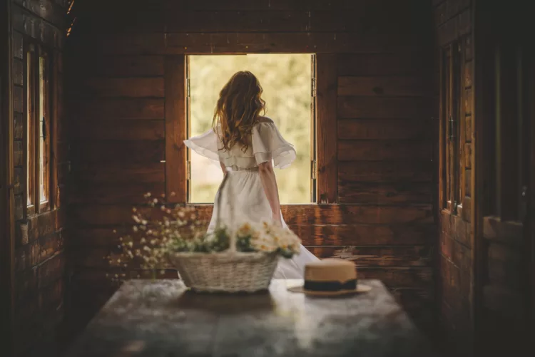 young lady in a dress by the window and a basket of flowers
