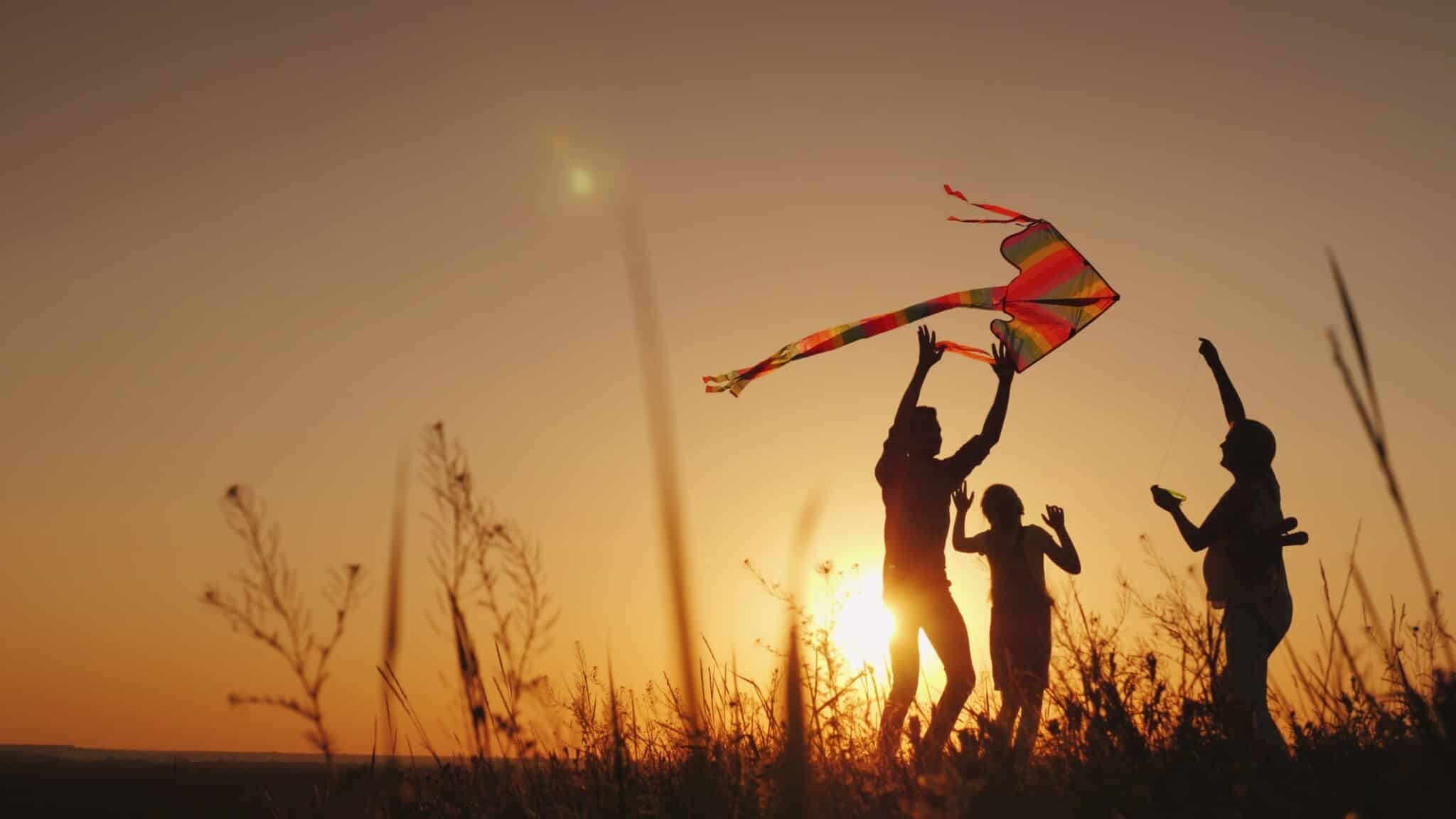 Happy family playing with a kite at sunset. 